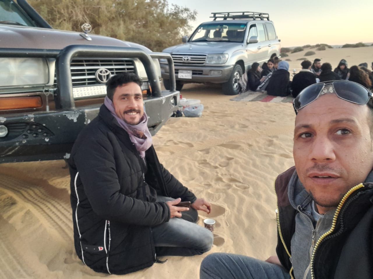 Yasser with his group and 4x4 jeeps at dusk in the desert, tea on the sand